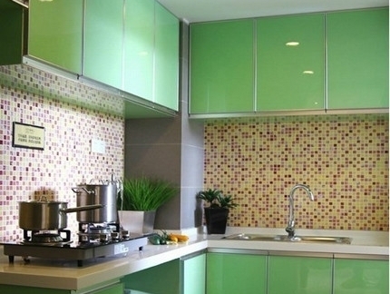 l型厨房绿色橱柜 中间的墙面是马赛克装饰 这个厨房很鲜艳